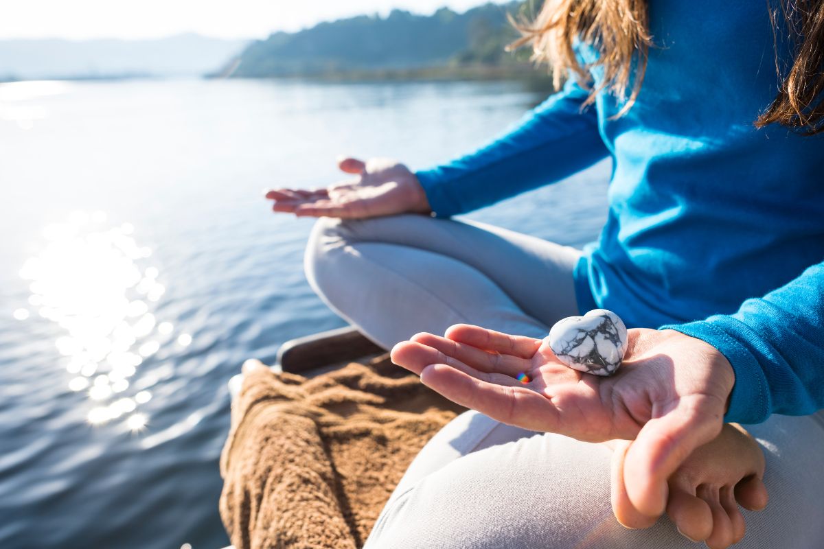 A lady meditating while taking gemstones on her hand.