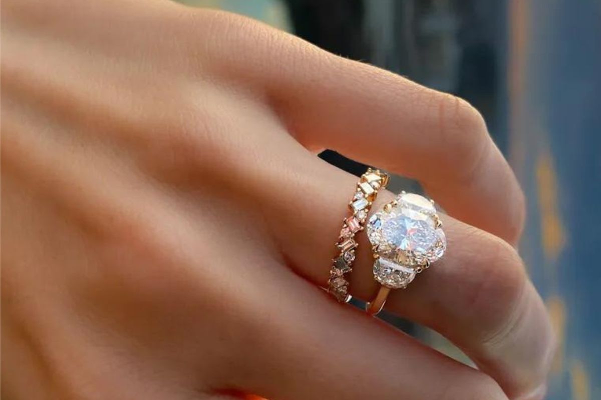 A lady wearing a diamond ring with half moon diamonds at the sides of ring.