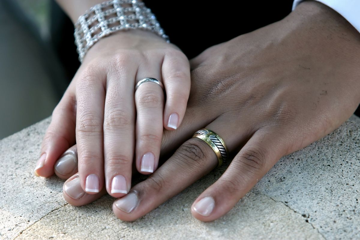A man and woman wear matching metal eternity bands, symbolizing commitment