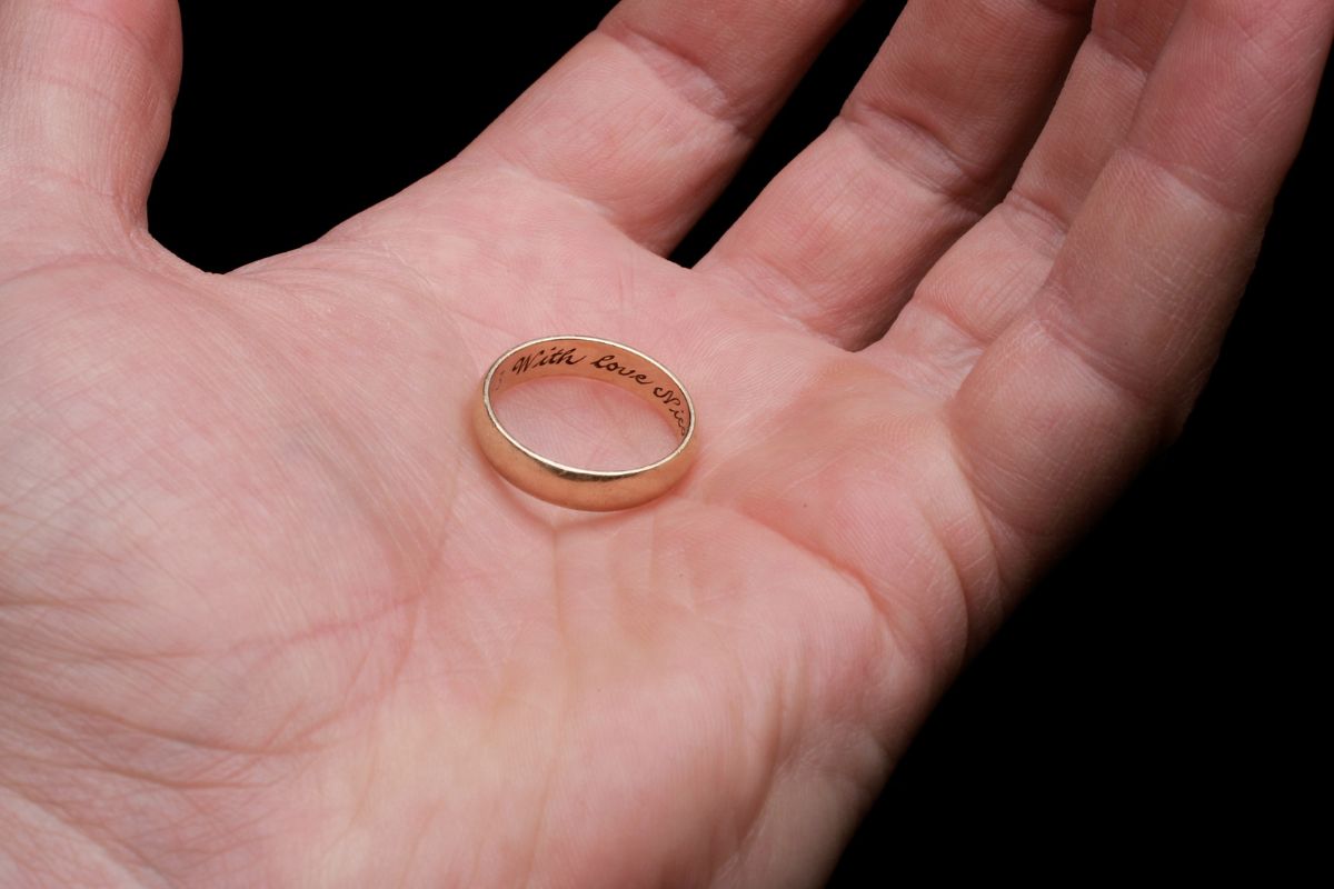 A man holding an engraved wedding ring in his hand