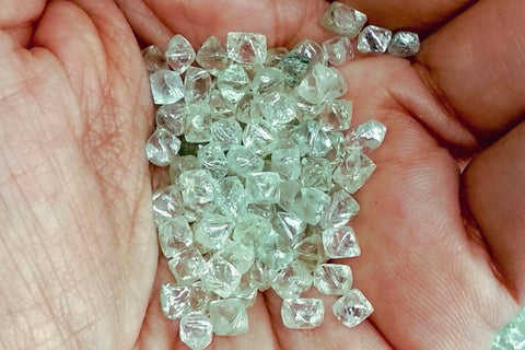 A man holding raw diamonds in his hand