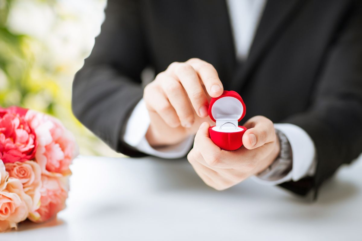 A man holds an eternity band in a ring box, ready to propose.