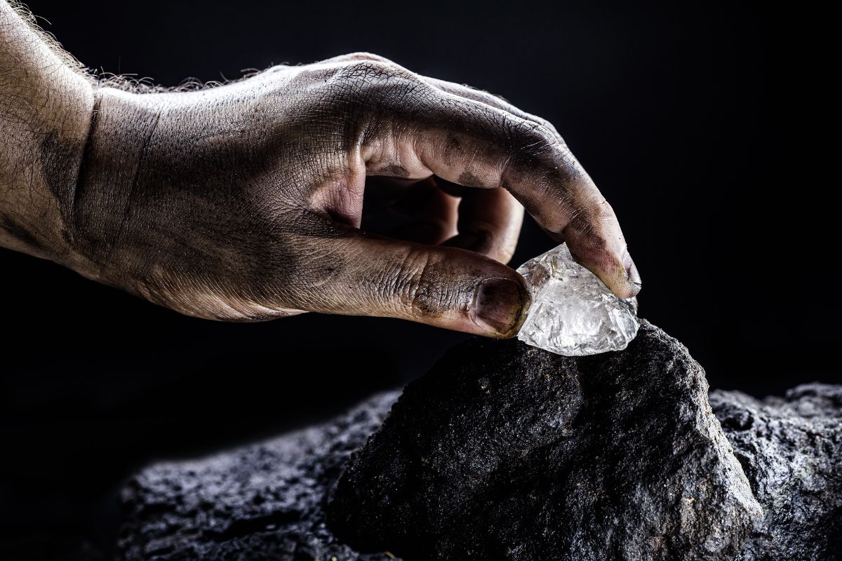 A man who works in a mine holding a natural old european cut diamond