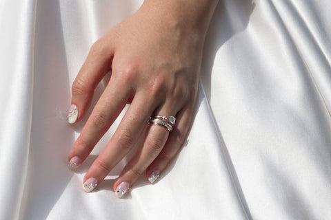 Beautiful hand wearing a wedding band above wedding ring