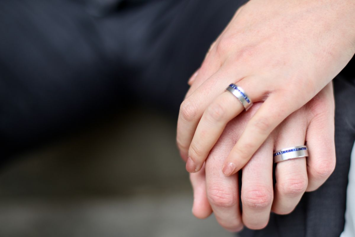 Couple holding hands while donning wedding bands