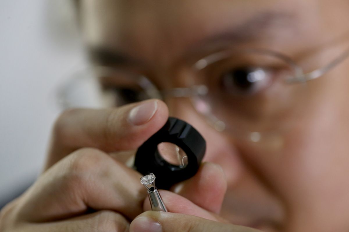 Person inspecting polished diamond through magnifying loupe