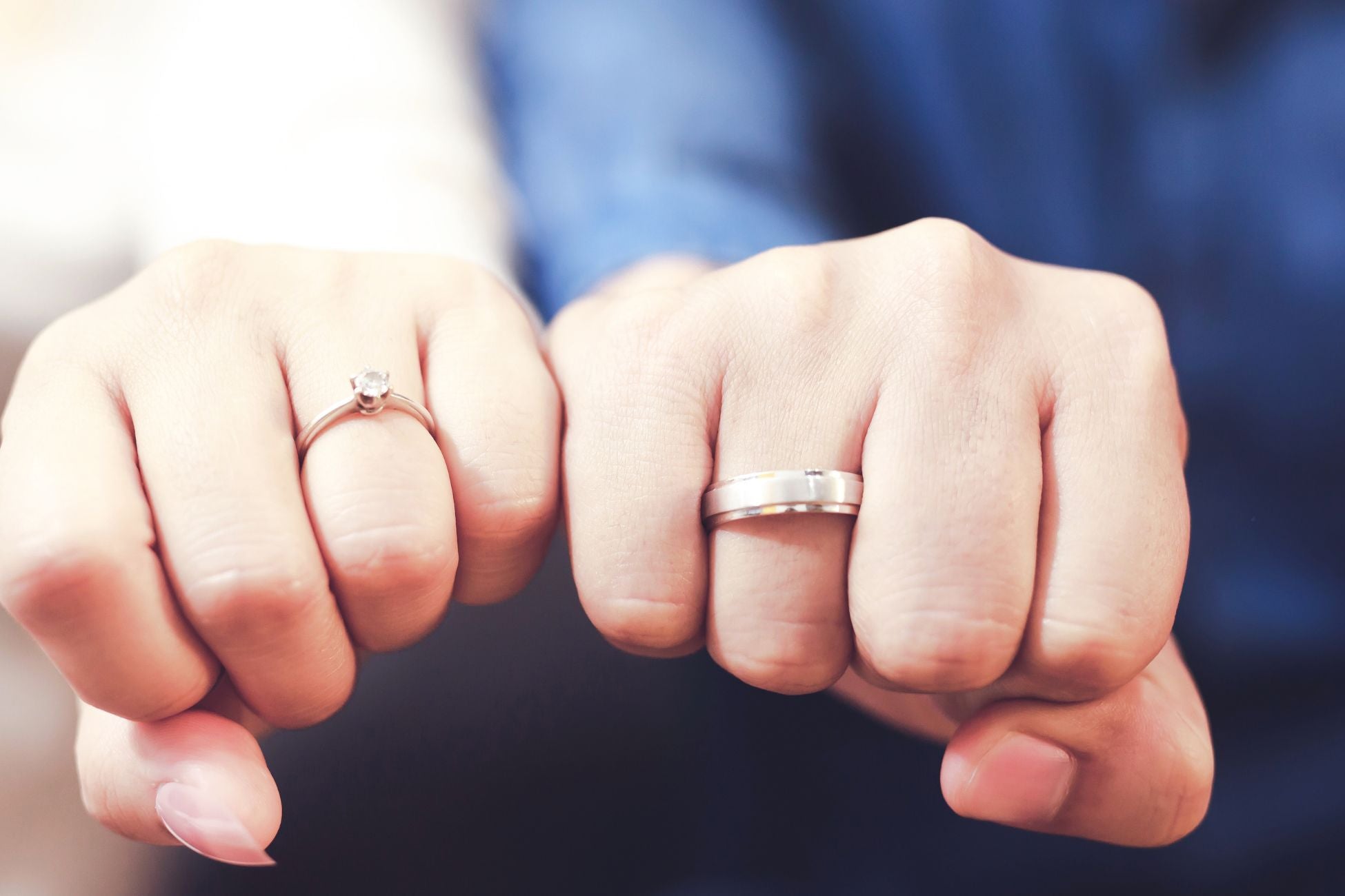 Two hands of a couple wearing engagement rings