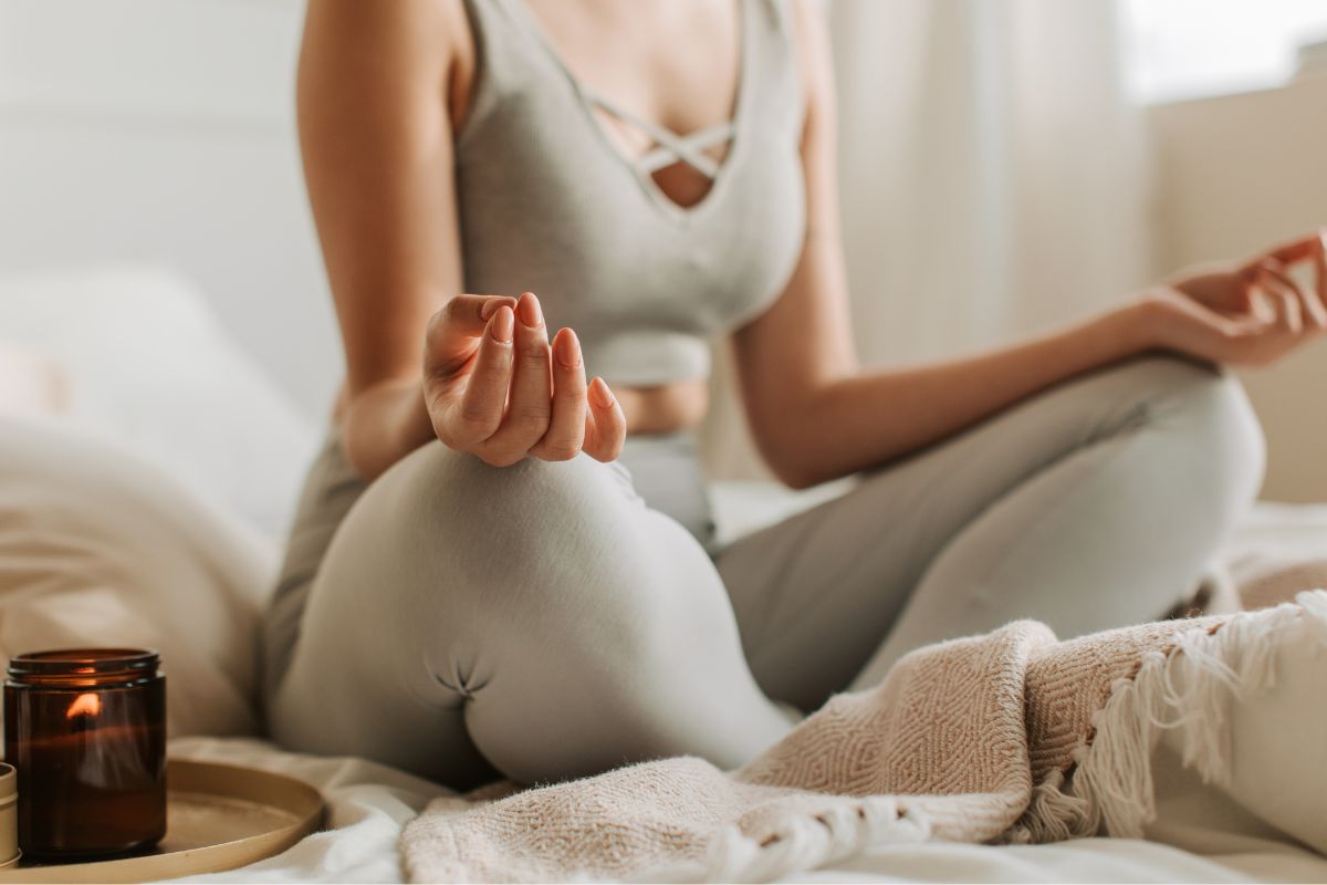 Woman meditating while sitting on bed