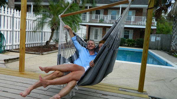 A man and woman happily sitting in a hammock chair together