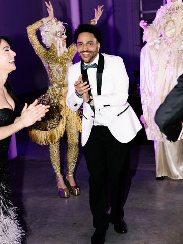 Groom, dancing, clapping hands in white jacket with black lapels.