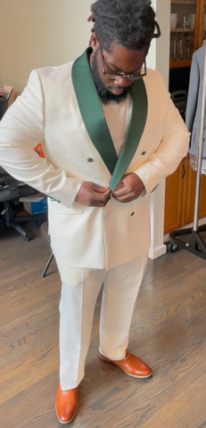 Man buttoning custom cream and green double breasted suit.