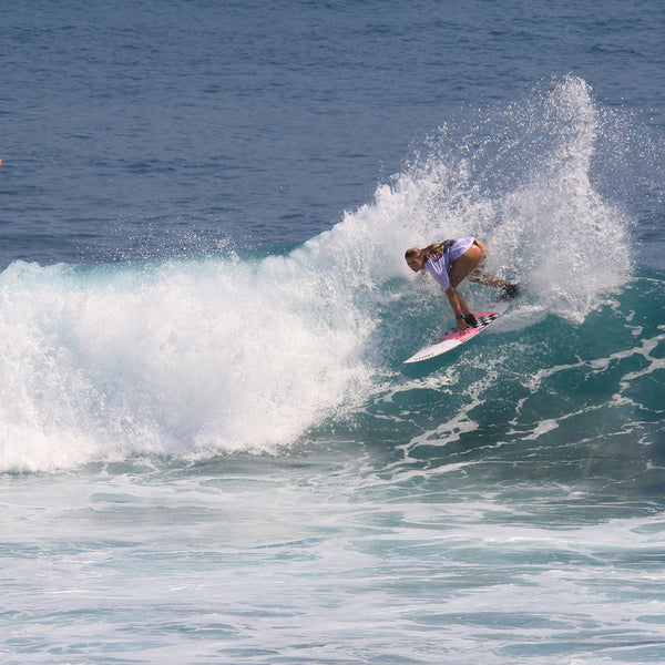 Rusty women's team rider riding surfboard in ocean