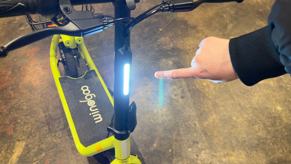 Reviewer pointing at front light on Windgoo B9 electric scooter