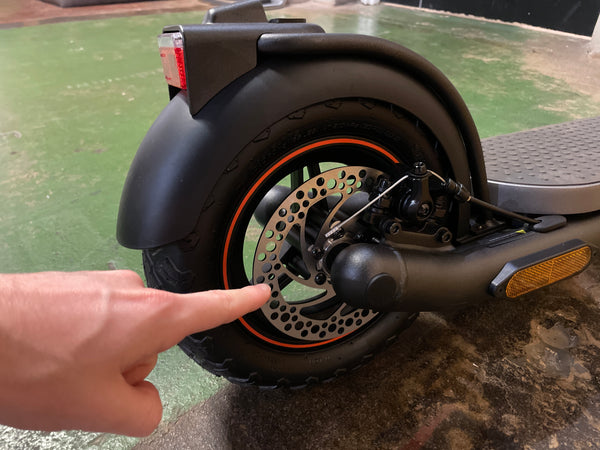 Reviewer points at brakes on Navee N65 electric scooter