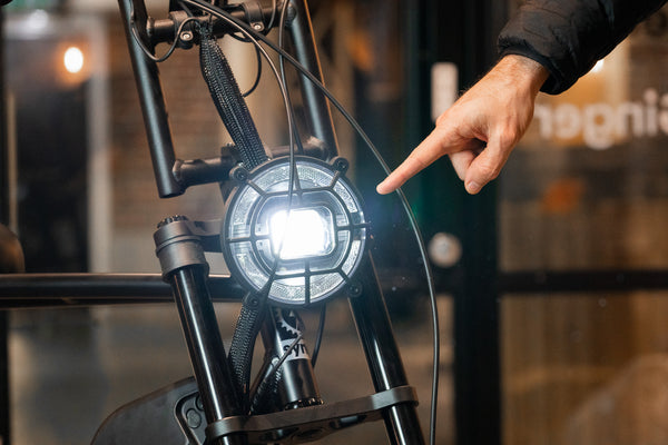 Reviewer pointing at front light on Synch Long Tail Monkey electric bike