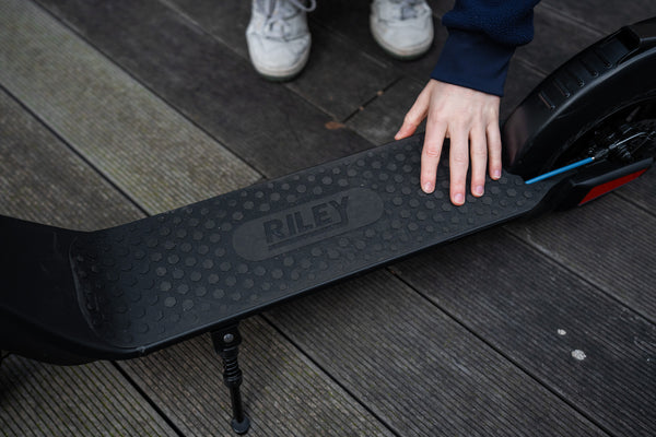 Reviewer highlighting Riley RS1 electric scooter deck