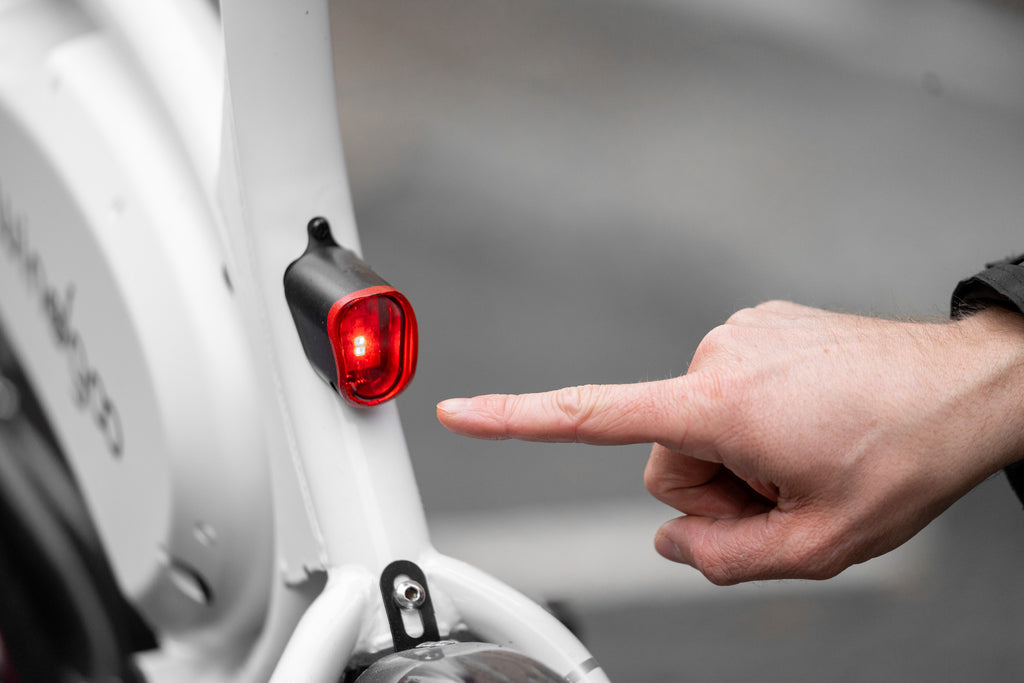 person pointing at rear brake light of Windgoo B3 electric bike