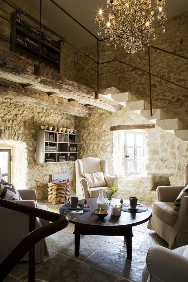 Love the contrast of the stone walls, the chandelier and the simple iron railing..