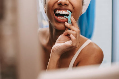 Close up of a young woman flossing her teeth