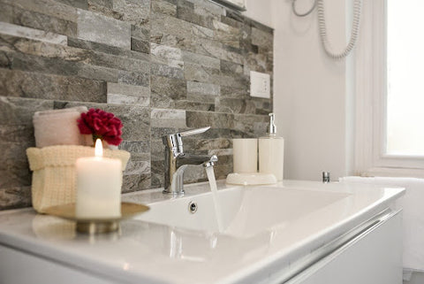 A beautiful bathroom sink with backsplash and lit candles