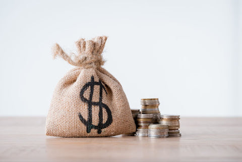 Bag of money next to a stack of coins