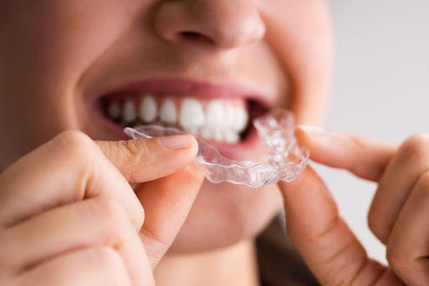 close-up of a smiling woman holding her night guard in front of her teeth