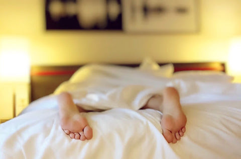 person sleeping in a bed, only feet are visible sticking out of covers