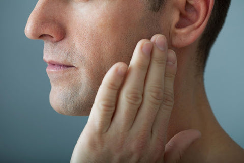 man holding the side of his face as if in jaw pain from TMJ/TMD