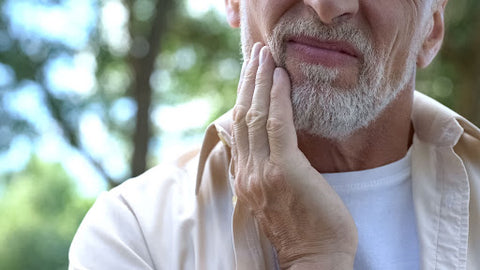 Older man holding jaw in pain, ways to alleviate TMJ