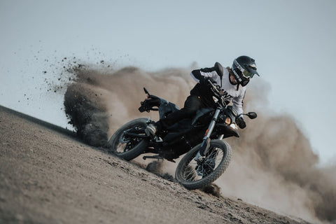 man riding his motorcycle in the dirt while wearing a SA1NT unbreakable top