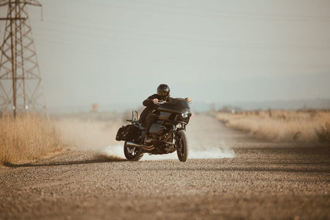 man skidding his motorbike on a dirt road with powerlines behind him