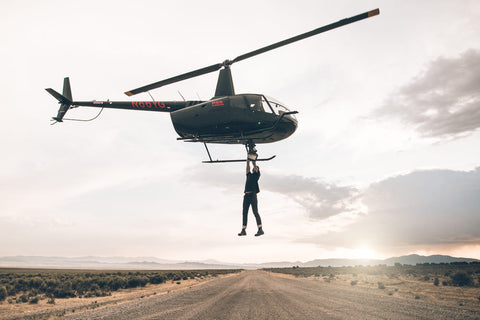 man hanging from helicopter from pair of jeans