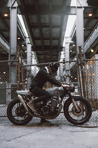 motorcyclist sitting on motorbike with fence in the background