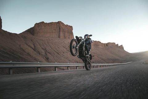 rider doing wheelie in desert