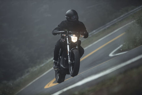 motorcyclist in black gear leaning on turn