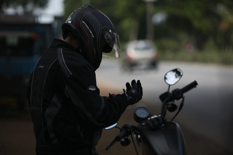 man sitting mon motorcycle looking at his hand