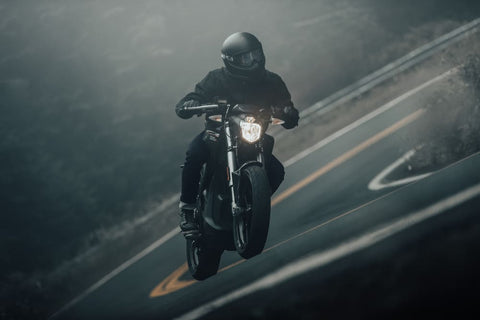 Man riding a black motorcycle on a road