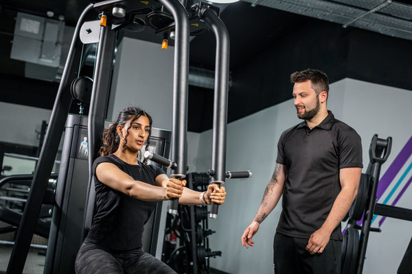 Personal trainer showing a client how to train with machines