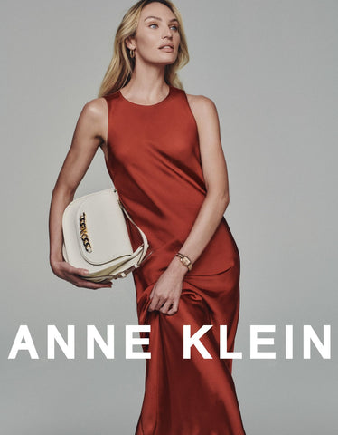 Image of Candice Swanepoel holding an Anne Klein Purse and wearing an Anne Klein dress with copy "anne klein" towards the bottom 