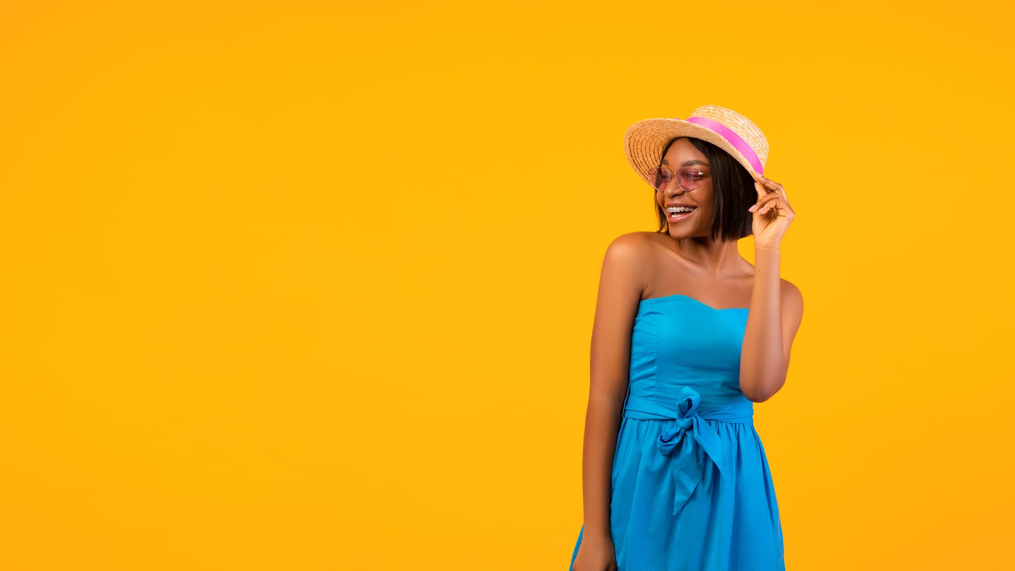 Casual Wedding Attire for Women image, Happy black woman in summer dress and straw hat looking aside at at empty space on orange background