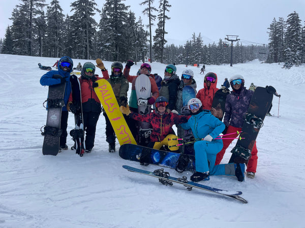 group of women standing together posing with snowboards
