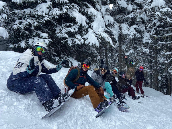 women on snowboards sitting together on the snow