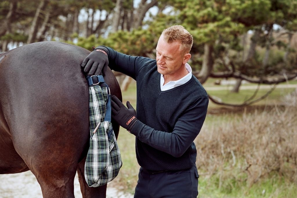 En mand tørrer sin hests våde hale med Siccaro Wrapido hestehale tørreposen