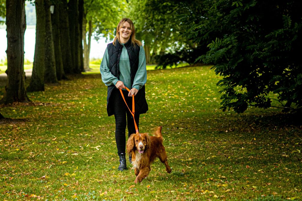 Ung kvinde går tur med rød cocker spaniel hund iført Siccaro Sealines hundesnor