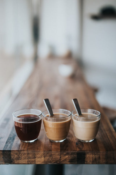 Three coffees on a table with spoons