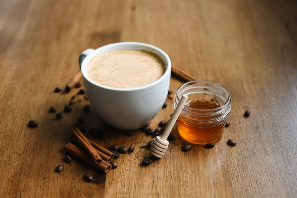 creamy coffee with baking spices and jar of honey on a table