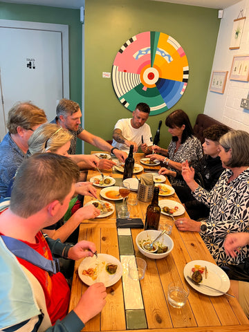 A group on a food tour of Leeds, sat around a table self-serving a variety of dishes including some of the best chips in Leeds