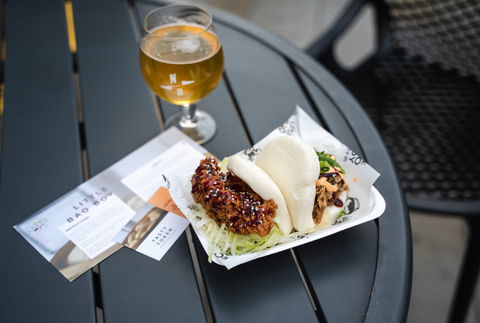 Two bao buns, next to one of the self-guided food tour information cards and tokens. This is one of the best places also to get chips in Leeds.