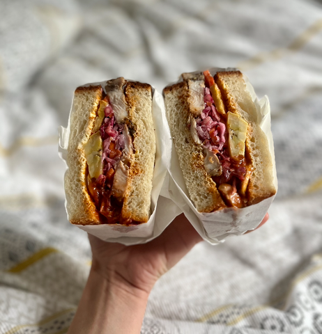 One of the best sandwiches in Leeds, from Things in Bread. The sandwich has been cut in half and is being held in one hand, showing the fillings.