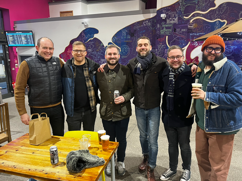 A group of six men in stood in Leeds Market smiling at the camera during a food tour